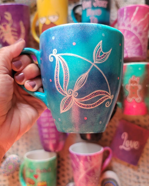 a hand-painted blue mug with a Sagittarius sign and blue and pink polka all around