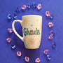 An Ivory Hand painted mug with the name ghada and small doodle suns and small hearts scattered all over the mug