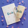 An Ivory Hand painted mug and Card with the name ghada and small doodle suns and small hearts scattered all.