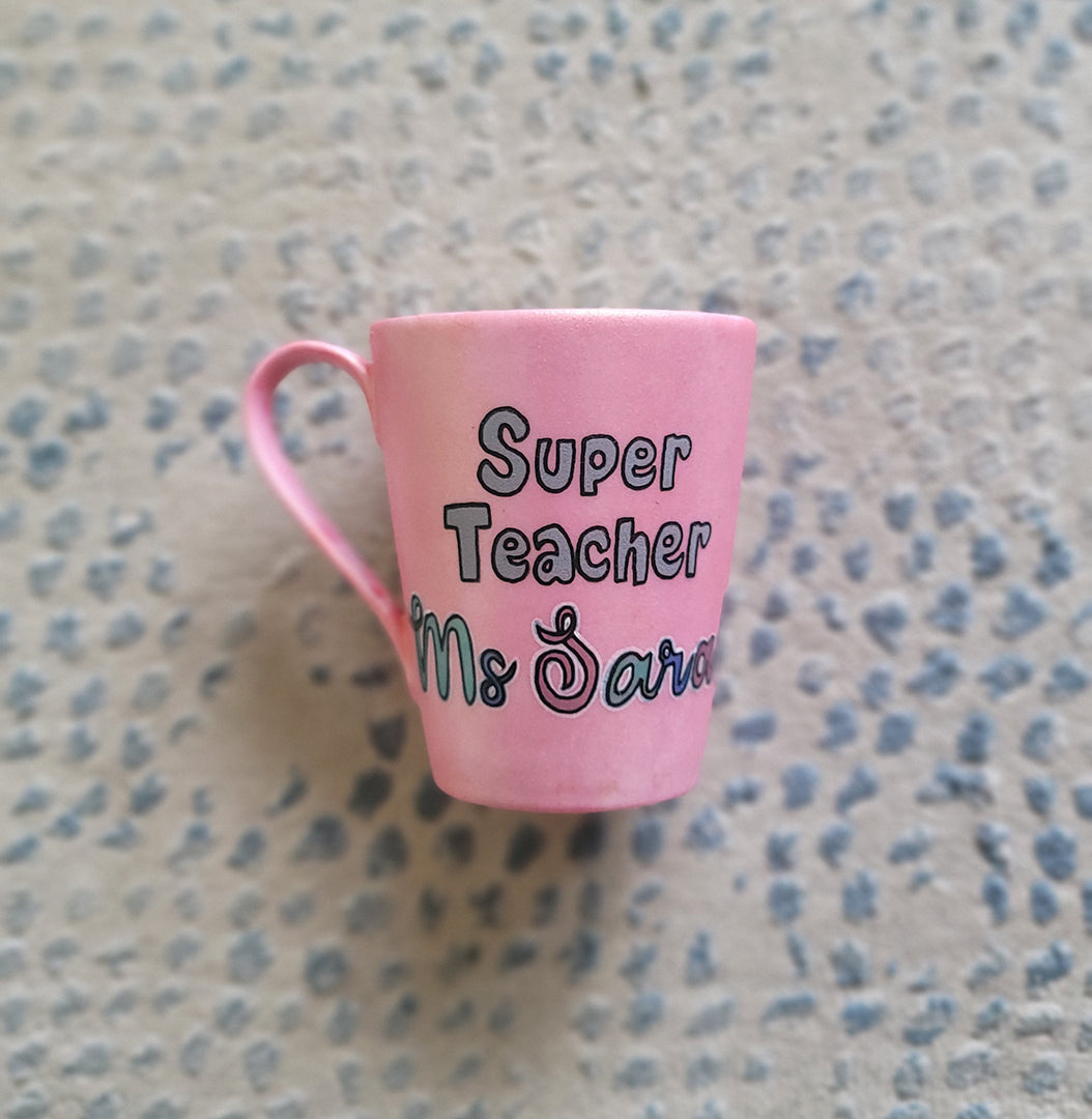 A Shimmery pink hand painted mug with the words "Super Teacher Ms.Sarah"