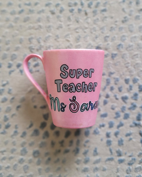 A Shimmery pink hand painted mug with the words "Super Teacher Ms.Sarah"