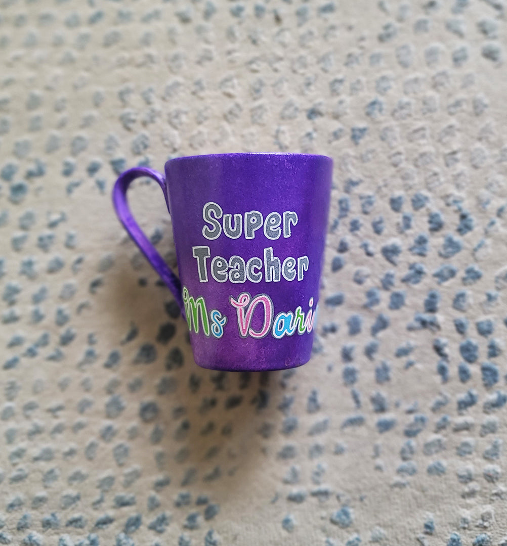 A Purple hand painted mug with the words "Super Teacher Ms.Darine"