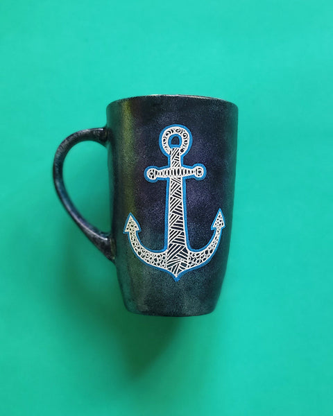 A Black sky hand painted mug with an anchor painted on it in patterns and outlined with blue