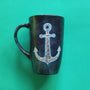 A Black sky hand painted mug with an anchor painted on it in patterns and outlined with blue