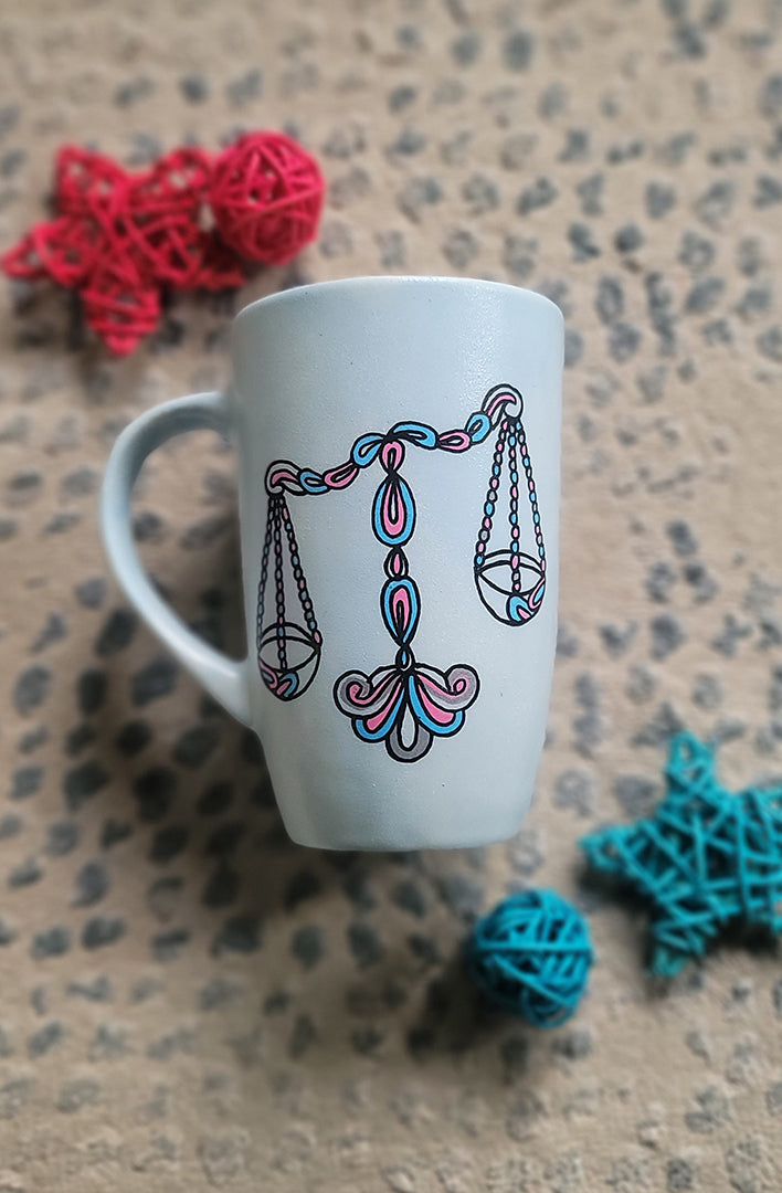 A Baby Blue hand painted mug with a libra design on it