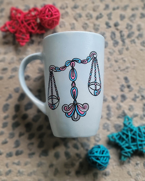 A Baby Blue hand painted mug with a libra design on it