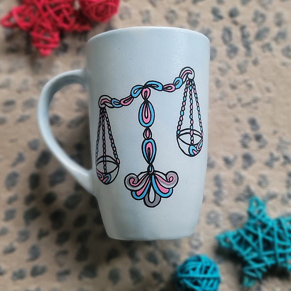 A Baby Blue hand painted mug with a libra design on it