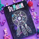 A Dark Sky hand painted notebook with a mandala drawn in white and the name 