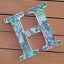 A white letter H with doodles in black and colored in with pink, lime green and light blue