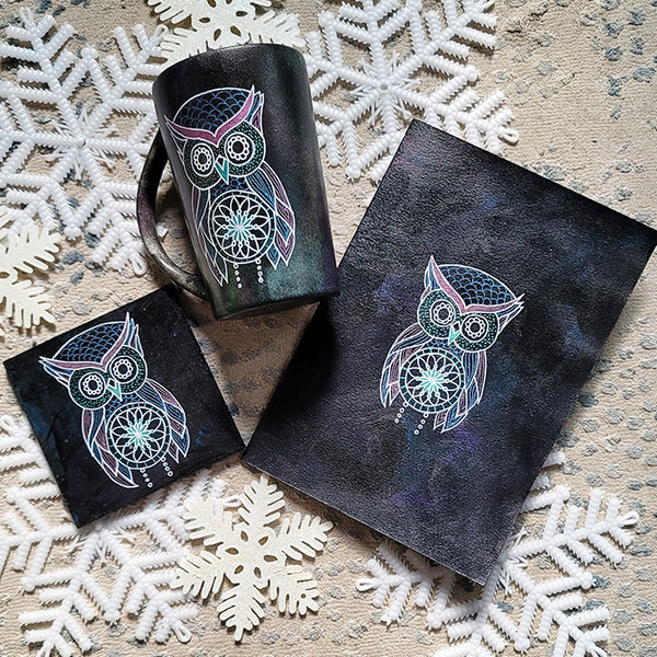 A Black Galaxy hand painted gift set containing a mug, card and coaster all with an owl design