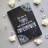 A Black Galaxy Hand painted notebook with 2 small mandala drawn in white in the opposite corners and the quote written in the center 