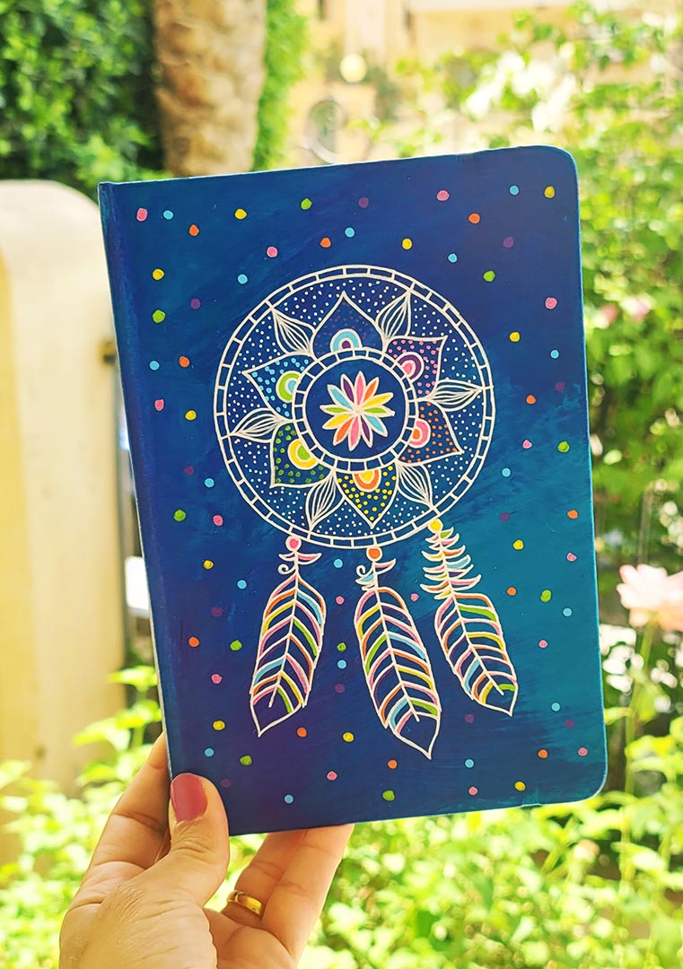 a Blue hand painted notebook with a dreamcatcher drawn in white