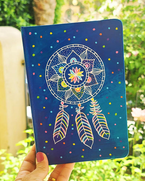 a Blue hand painted notebook with a dreamcatcher drawn in white