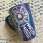 A bluish galaxy hand painted mug with a dreamcatcher in white and colored in with (pink, yellow, purple blue, green and orange)