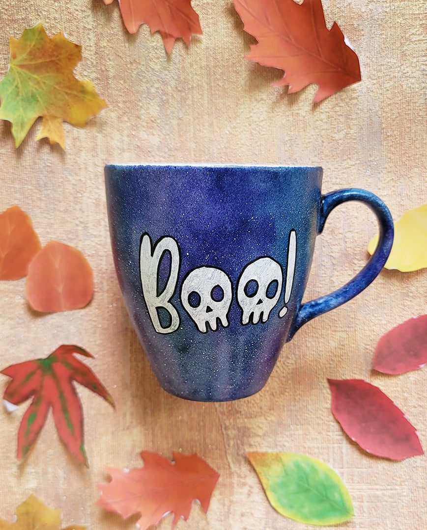 a bluish hand painted mug with the word "BOO' on it