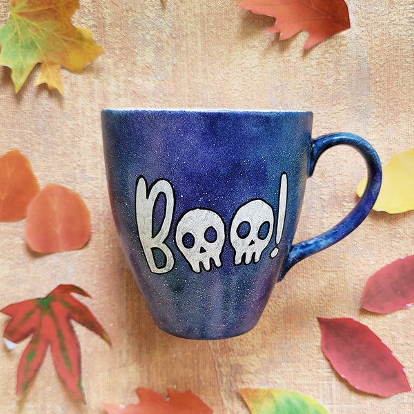 a bluish hand painted mug with the word "BOO' on it