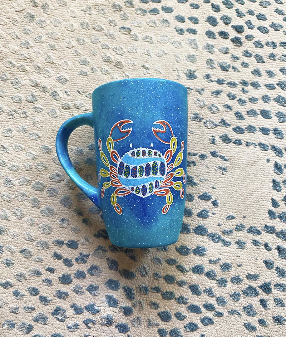 A hand-painted blue galaxy mug with cancer sign drawn on it