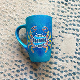 A hand-painted blue galaxy mug with cancer sign drawn on it