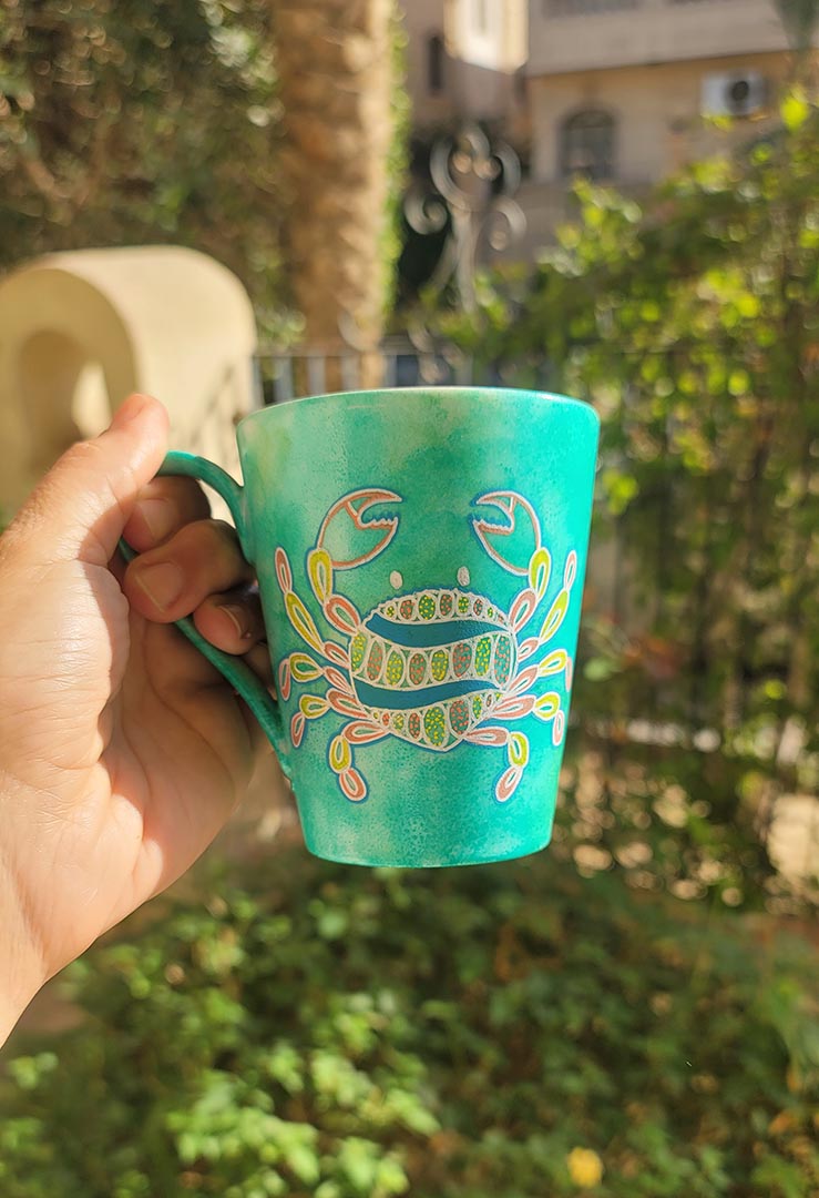 A hand-painted green  mug with cancer sign drawn on it