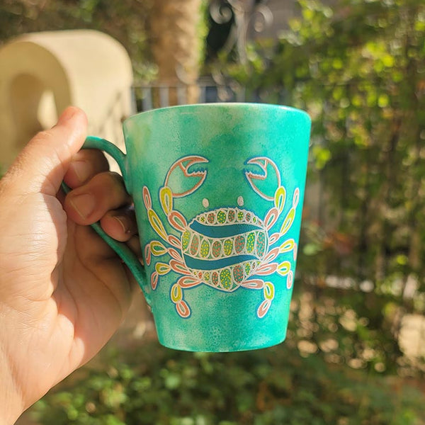 A hand-painted green  mug with cancer sign drawn on it