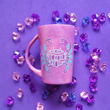 A hand-painted pink galaxy mug with cancer sign drawn on it