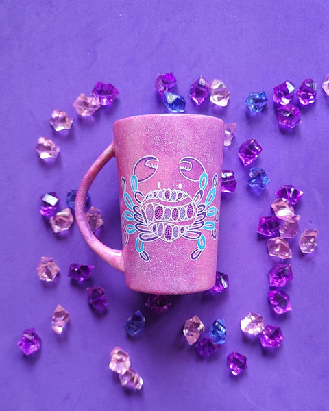 A hand-painted pink galaxy mug with cancer sign drawn on it