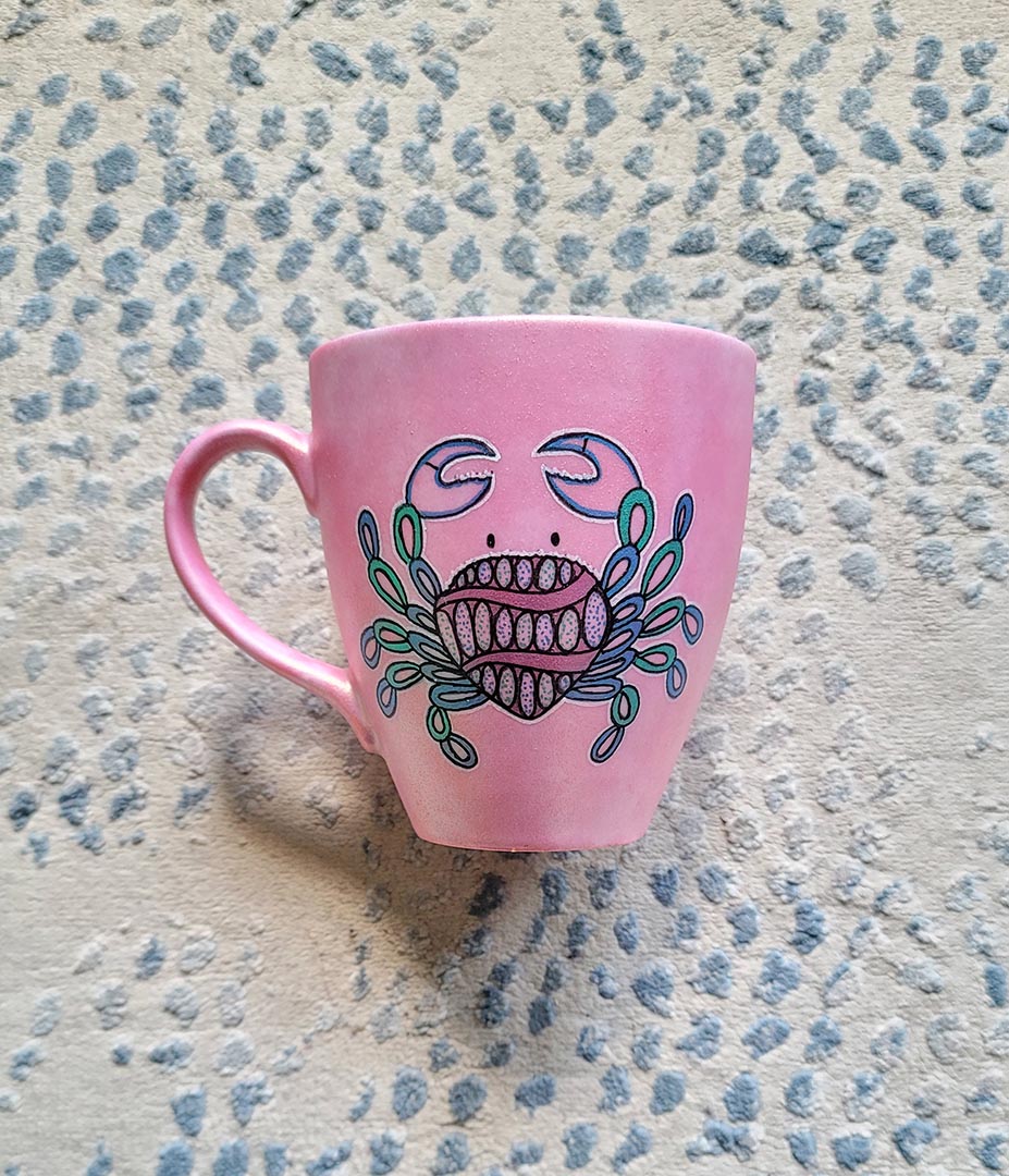 A hand-painted shimmery pink mug with cancer sign drawn on it