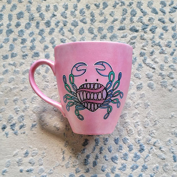 A hand-painted shimmery pink mug with cancer sign drawn on it