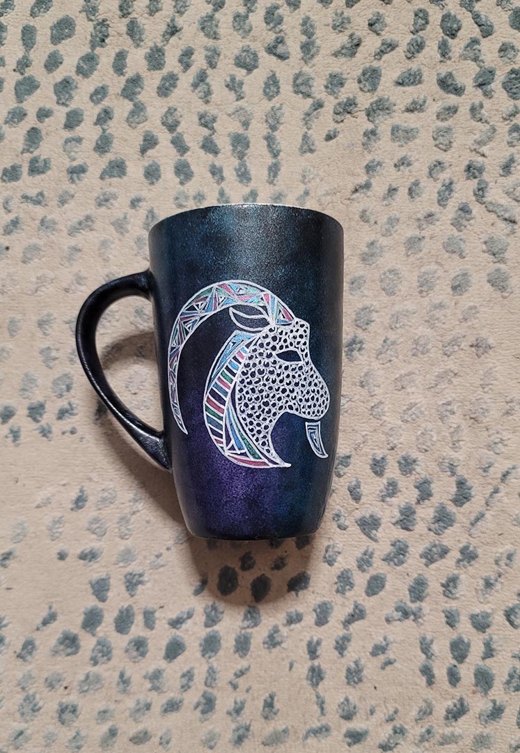 A Hand-painted dark galaxy mug with Capricorn sign in white and colored with patterns of pink blues and greens