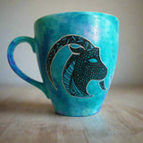 A Hand-painted blue galaxy mug with Capricorn sign in black and colored in with patterns of blue, green and black