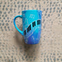 A Blue Hand painted mug with piano keys drawn moving all over hz on the mug and cats on it and below it , with musical symbols scattered