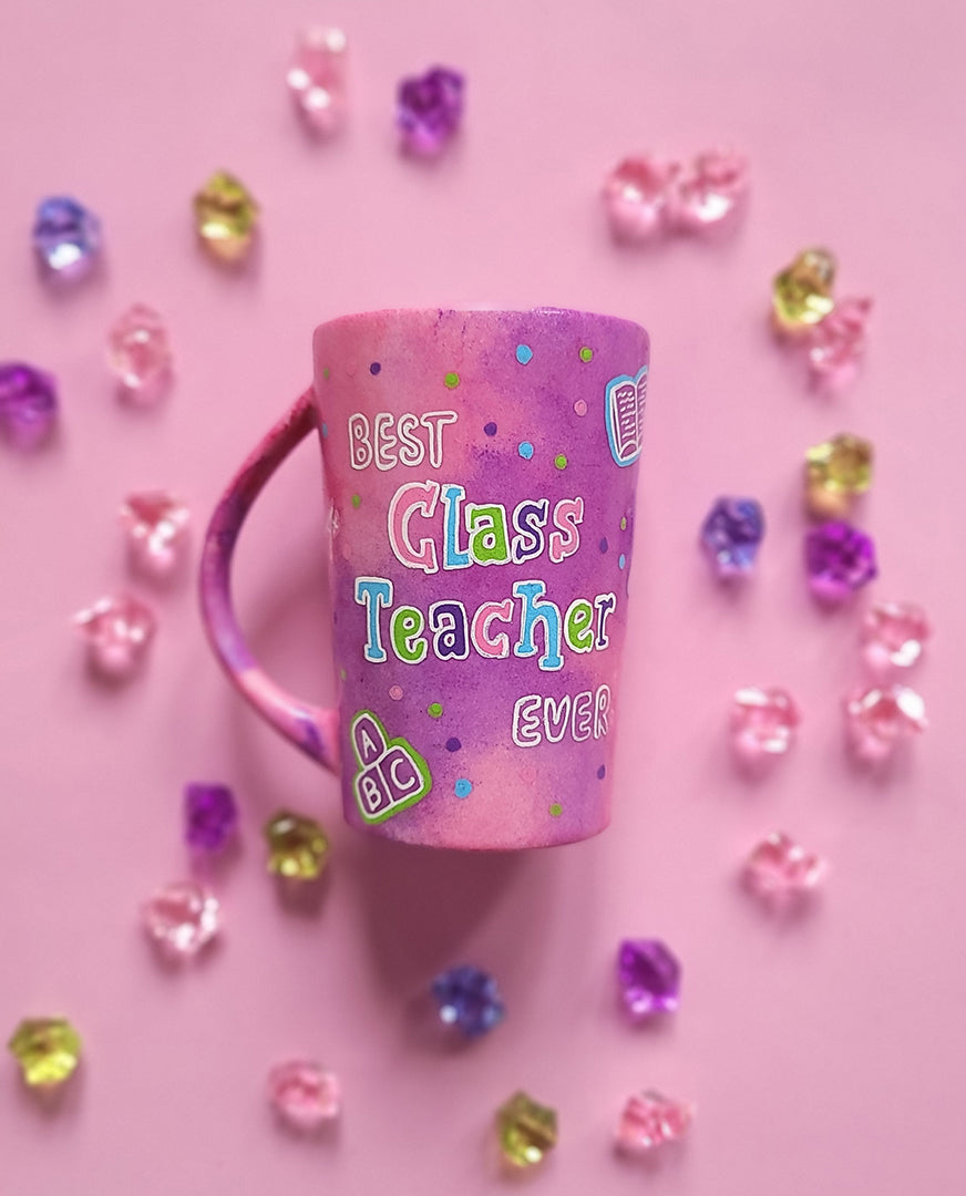 A Pink Hand painted Mug with the words "Best Class Teacher Ever" and school items scattered all over