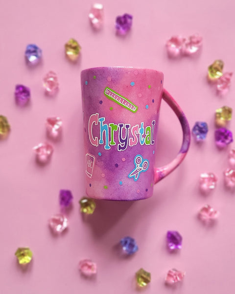 A Pink Hand painted Mug with the name "Chrystal" and school items scattered all over