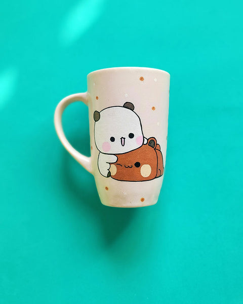 A Pale Pink Hand painted mug with the design of 2 cute bears cuddling (one bear is white and the other is brown)