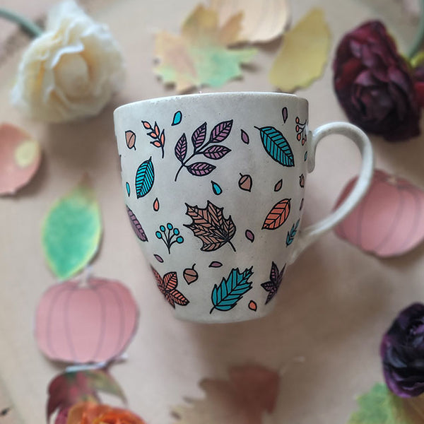 A Taupe Hand painted mug with autumn leaves scattered all over