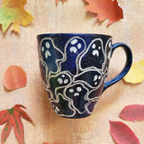 A Bluish Galaxy hand painted mug with ghosts painted all over in white and outlined with silver