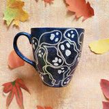 A Bluish Galaxy hand painted mug with ghosts painted all over in white and outlined with silver