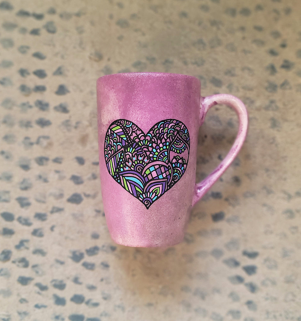 a Pastel Pink hand painted mug with a heart drawn in black filled with colorful patterns