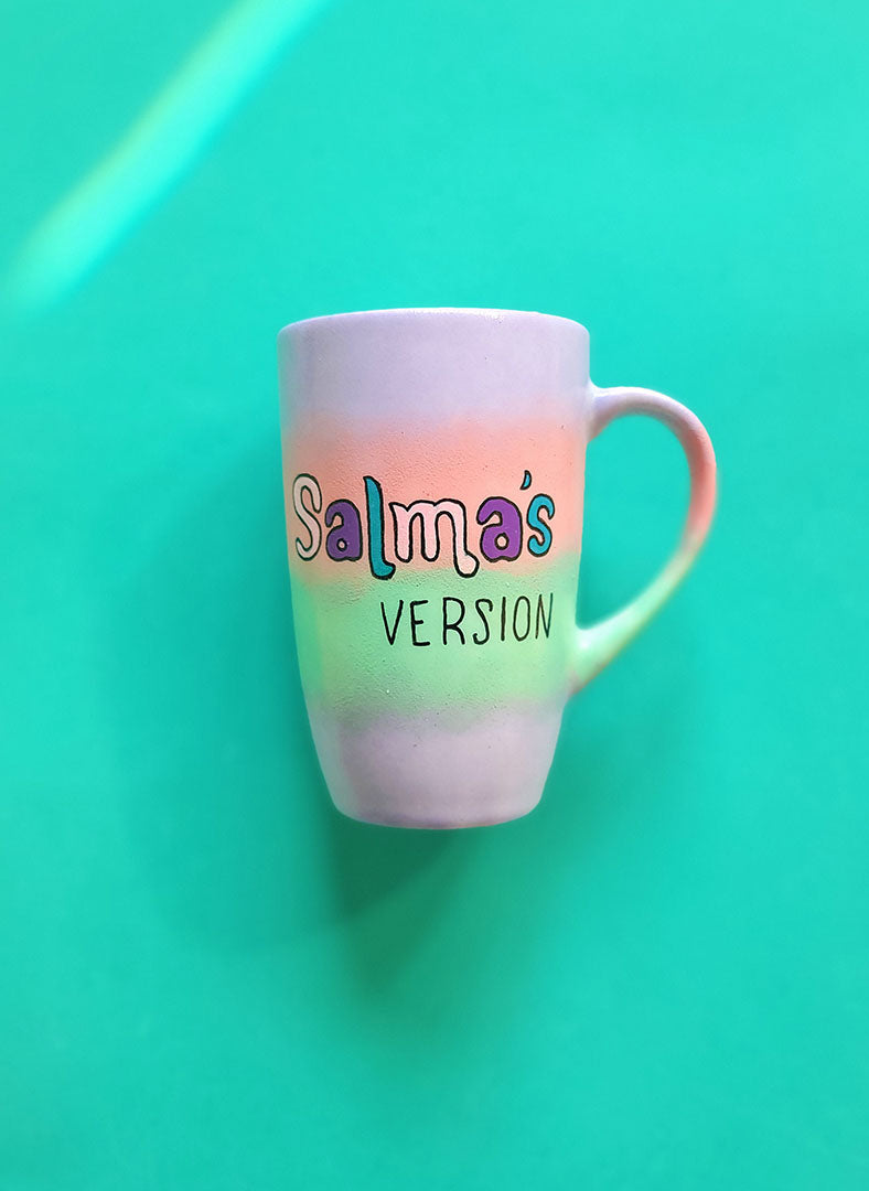 A gradient hand painted mug (lilac-peach-mint-lilac) with the sentence "Salma's Version"