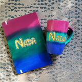 A Gift Set Hand painted in gradient colors (pink-green-blue) containing a mug and notebook with the name Nada written in the center in yellow