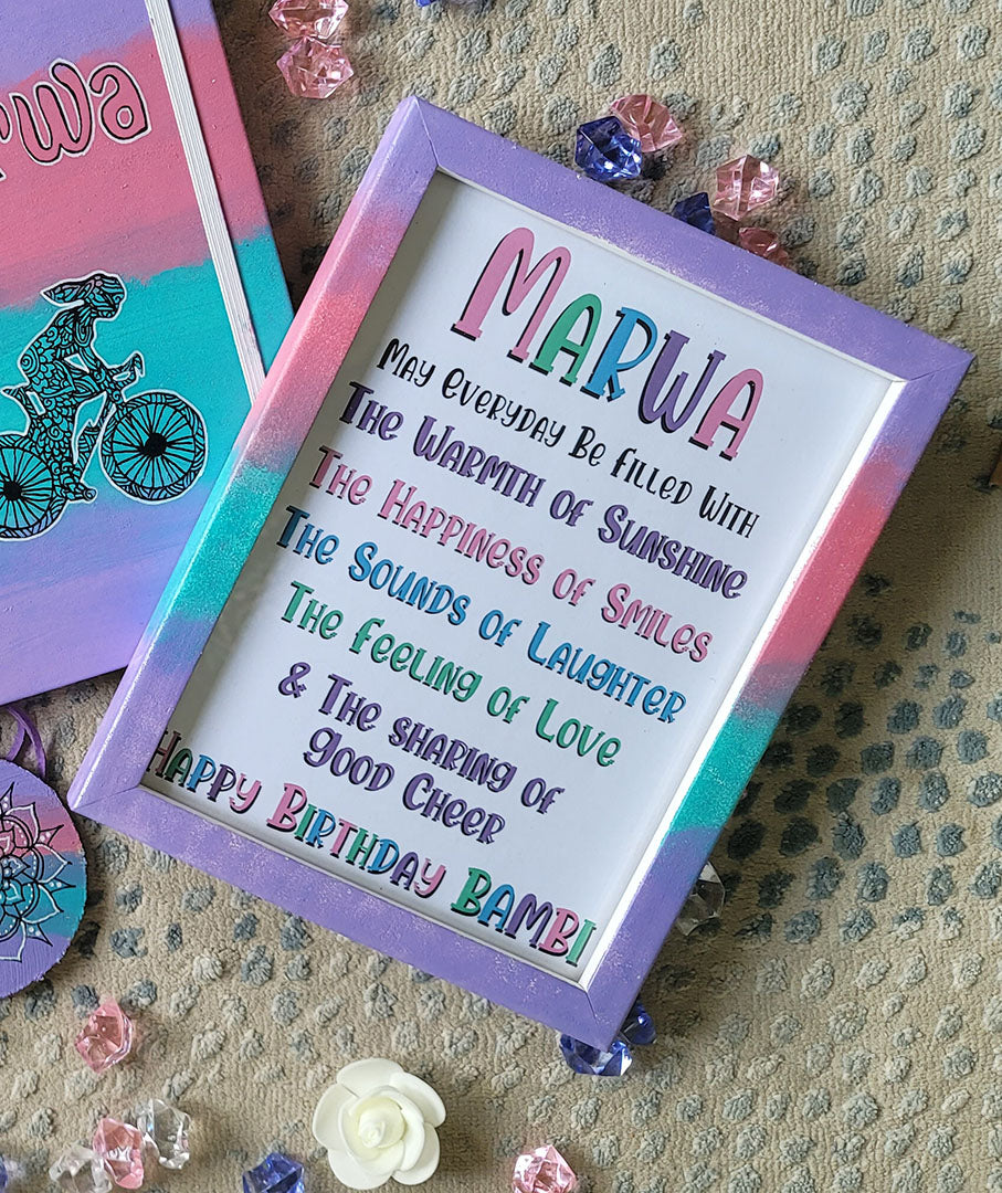 a gradient hand painted wooden frame (lilac-pink-mint-lilac) with the following words written inside "Marwa, may everyday be filled with the warmth of sunshine, the happiness of smiles, the sounds of laughter , the feeling of love and the sharing of good cheer. Happy birthday Bambie"