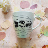 an ivory hand painted mug with a mummy drawn all over it and the name 'Marwa' peaking from behind