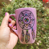 A Pastel Pink hand painted mug with a dreamcatcher in black and colored in with (pink, yellow, purple blue, green and orange)