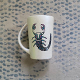 A Pearl white Hand painted Mug With a Scorpio Design on it in Black and colored in pinks, greens and blues