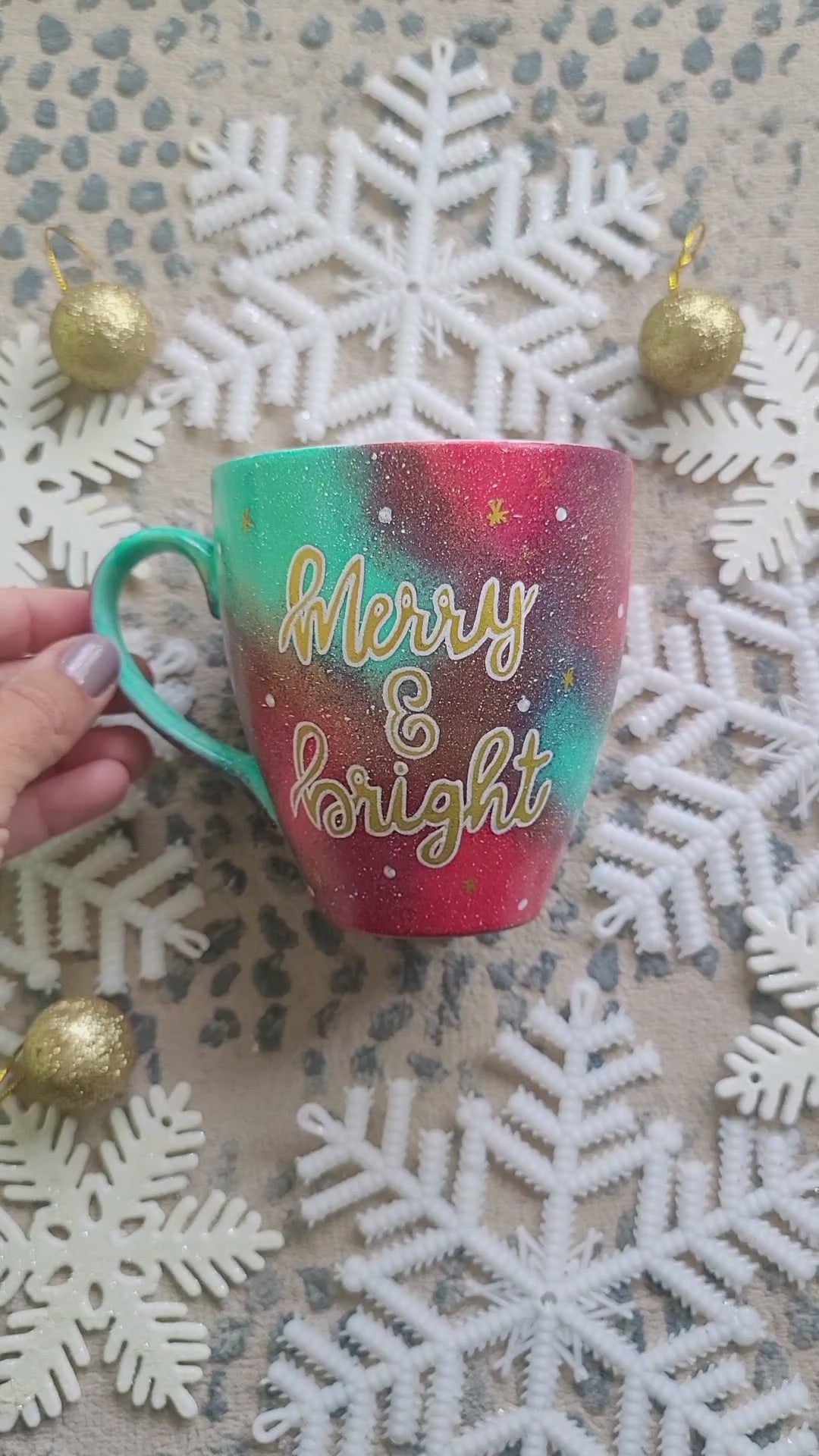 A Christmas galaxy colored hand painted mug with the words "Merry and Bright" written gold with white dots and gold stars scattered all over and the other side has the name Abir