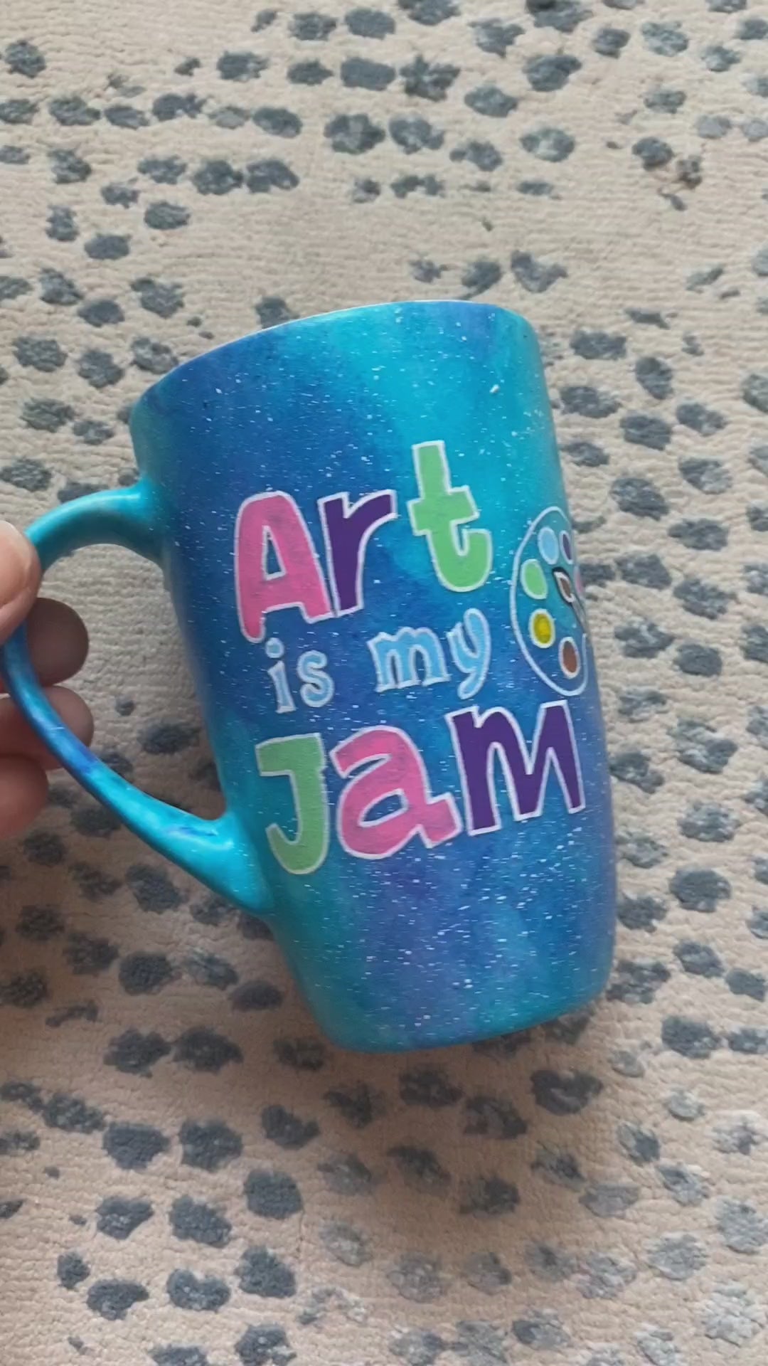 A Blue Galaxy Hand painted mug with the words "Art is my Jam" and a color palette drawn and the other side has the name "Sarah"