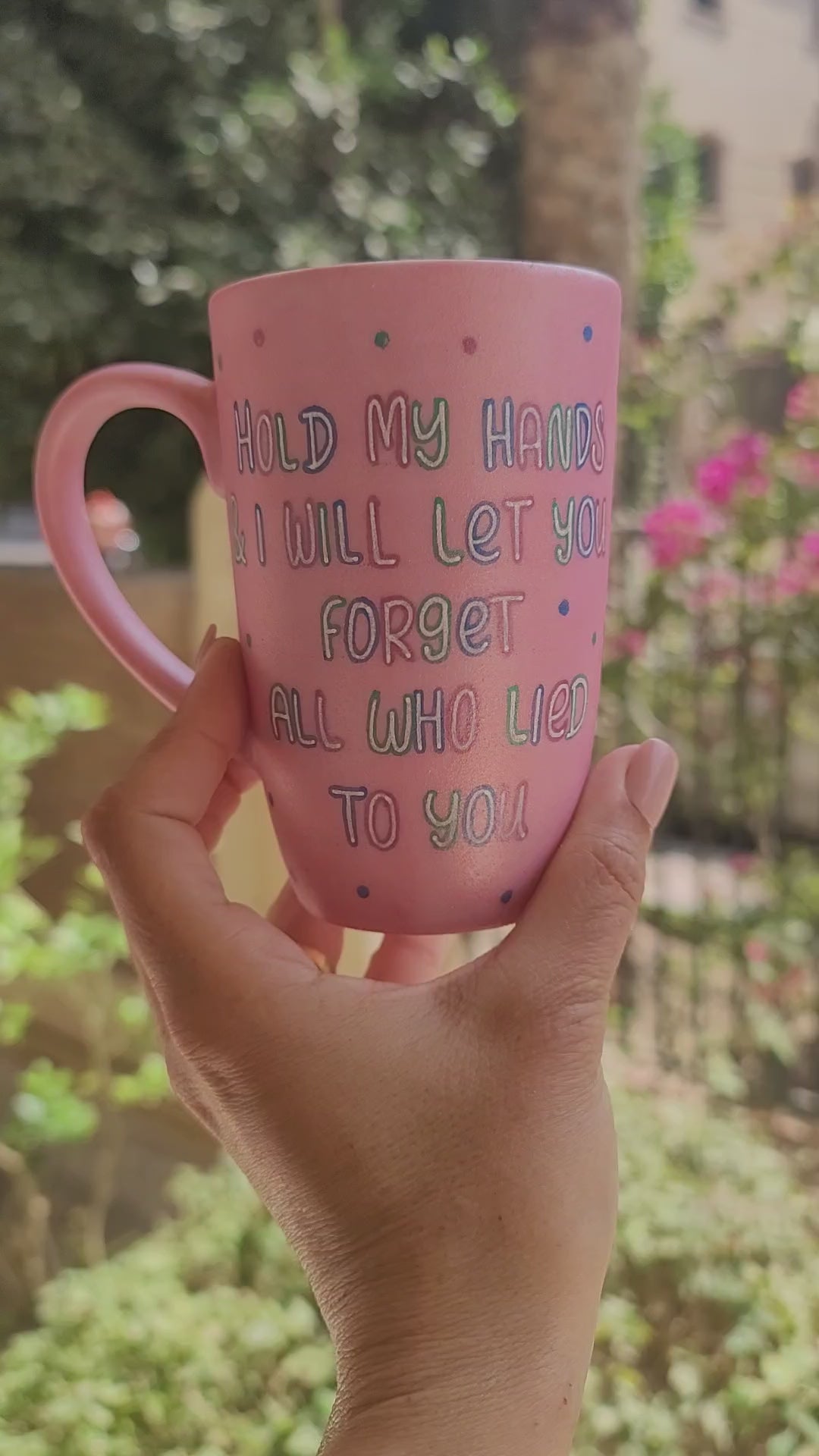 A hand-painted shimmery pink mug with the words "Hold my hand and I will Let you forget all who lied to you" and the other side has the name "marvel"