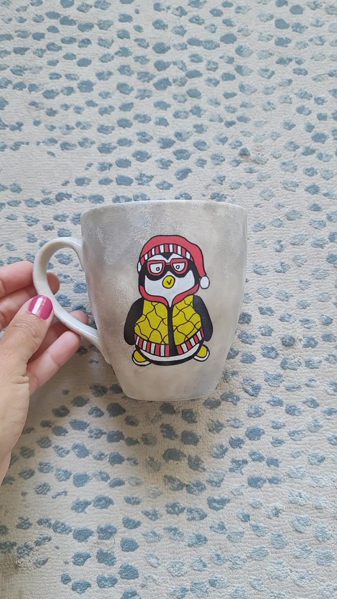 A Taupe hand painted mug with fully dressed penguin drawn on one side and the other side has the words "I'm a penguin at heart"