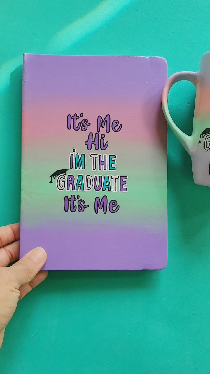 A Gradient hand painted mug and notebook (lilac-peach-mint-lilac) with the sentence "it's me ,Hi , I'm the Graduate it's me" and on the other side of both it's written "Salma's Version"