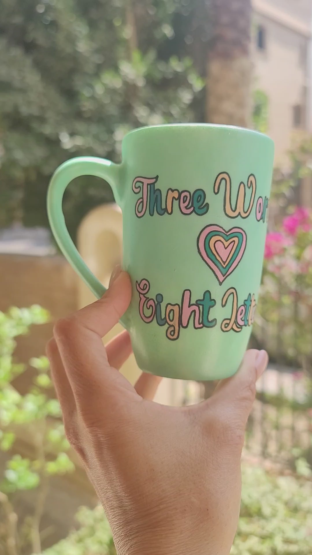  A Hand painted green Mug with the words "three words, Eight Letters" written and a heart place in between the two sentences on one side, and the name "Fayrouz" written on the other side